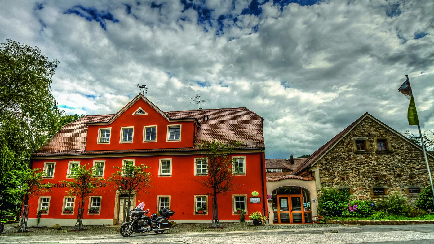 Rotes Barockgebäude mit Nebengebäude unter Wolkenhimmel